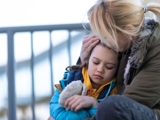 Woman hugging child looking sad