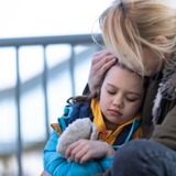 Woman hugging child looking sad