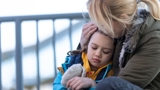 Woman hugging child looking sad