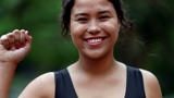 Photo of a young woman smiling, holding up her right hand in a fist.