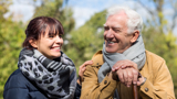 Older man outside, smiling, with a support worker