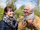 Older man outside, smiling, with a support worker