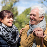 Older man outside, smiling, with a support worker