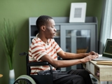 Photo of a man, in a wheelchair, sat at a laptop.