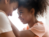 A mother and her daughter embracing, touching foreheads.