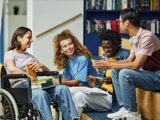 Photo of 4 young people in a college sitting and talking. 