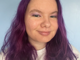 Photo of person with purple hair smiling at camera
