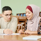 Two young adults sat at a table looking over papers.